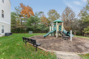 Exterior Acclaim at Sterling Playground, soft landing ground, wood perimeter, autumn foliage in background, neutral toned building, meticulous landscaping, photo taken on a sunny day.