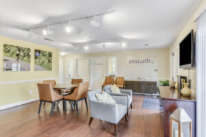 Interior Acclaim at Sterling lobby, wood floors, lounge chairs throughout lobby, pale yellow walls, avanath signage upon entering lobby, nature photographs on walls.
