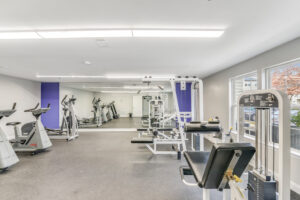 Interior Fitness Center, padded floor, mirrored wall, elliptical machine, stationary bikes, treadmill, various weight lifting machines.